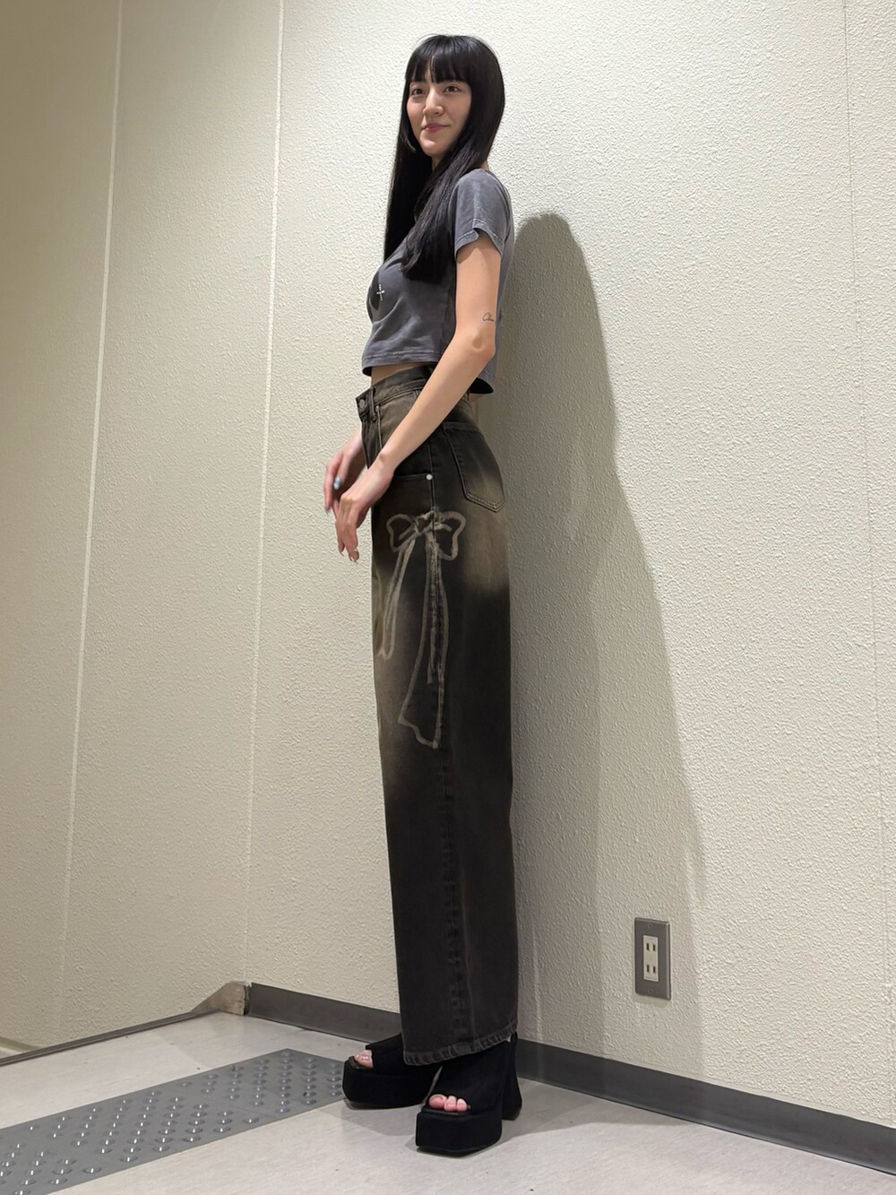 ブラック系のデニムパンツ、ブラック系のサンダル、グレー系のTシャツ/カットソーを着用したレディースの夏コーディネートの2枚目の写真