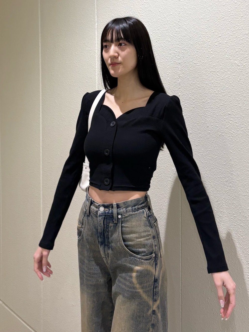 ブラック系のブーツ、ブルー系のデニムパンツ、ホワイト系のハンドバッグを着用したレディースの春コーディネートの8枚目の写真