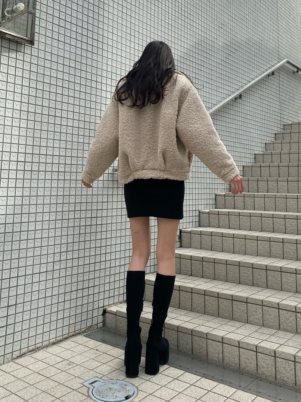 ブラック系のワンピース、ホワイト系のブルゾン、ブラック系のブーツを着用したレディースの冬コーディネートの4枚目の写真