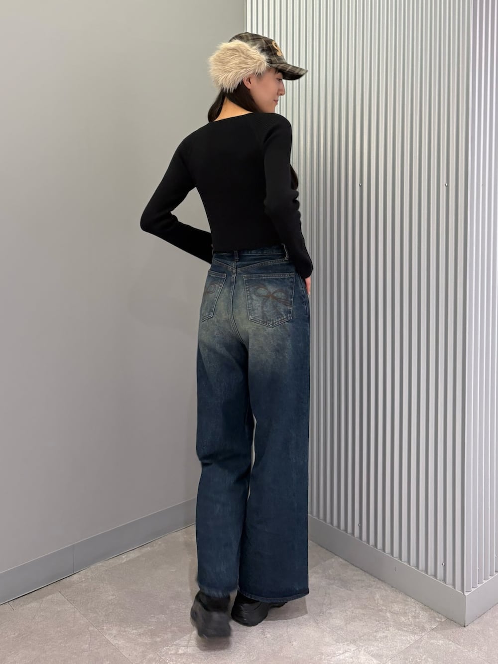 ブルー系のデニムパンツ、ブラック系のニット/セーター、ブラック系のスニーカーを着用したレディースの秋コーディネートの3枚目の写真