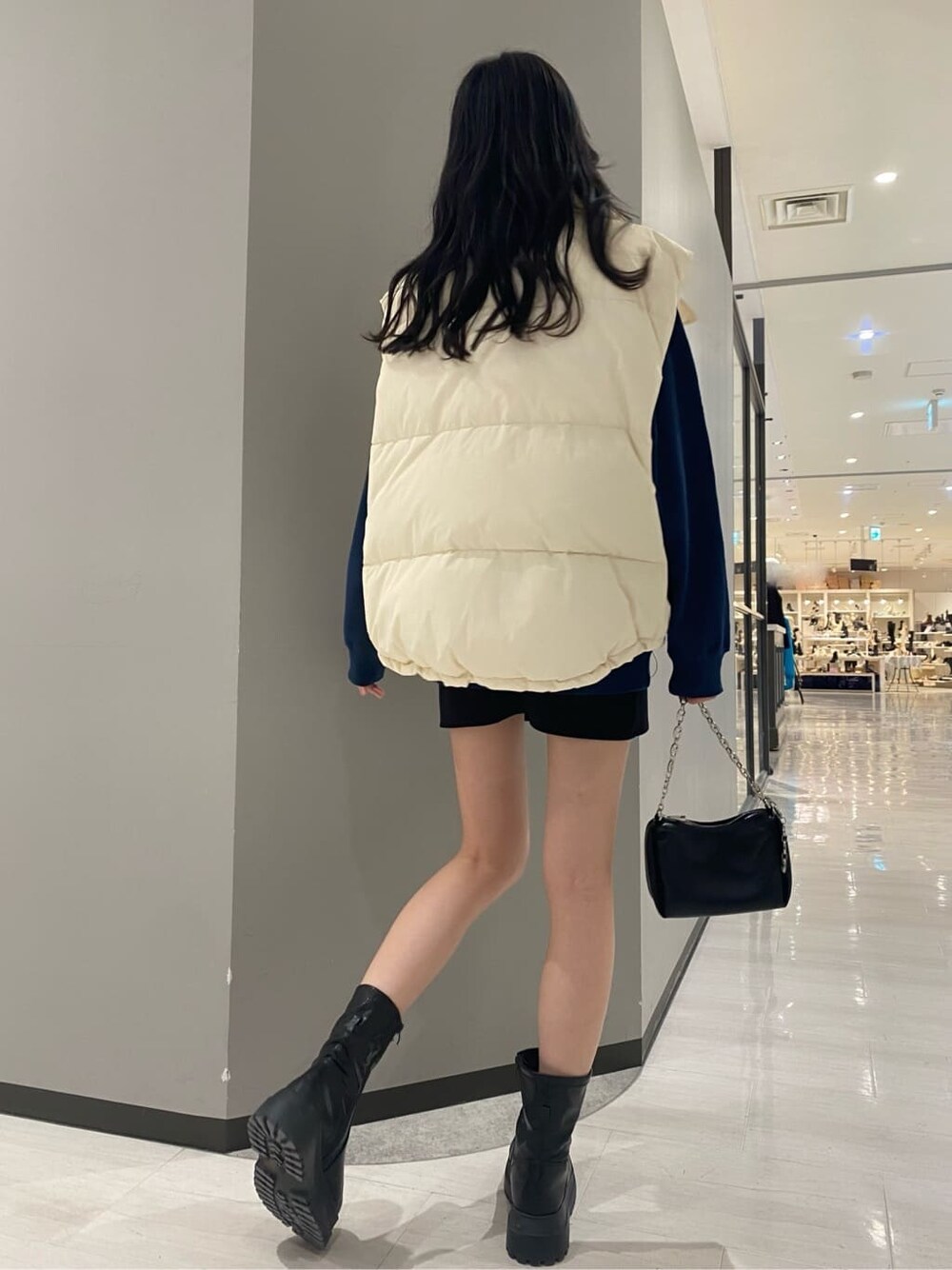 ブラック系のスカート、ホワイト系のダウンベスト、ブルー系のスウェットを着用したレディースの秋コーディネートの2枚目の写真