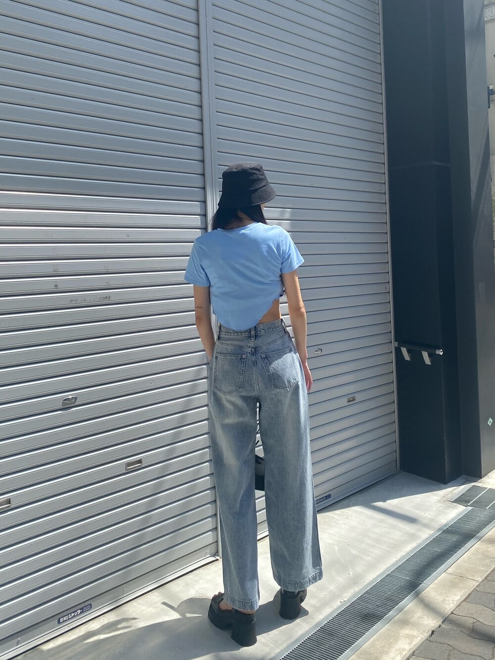 ブルー系のデニムパンツ、ブラック系のサンダル、ブラック系のハンドバッグを着用したレディースの夏コーディネートの2枚目の写真