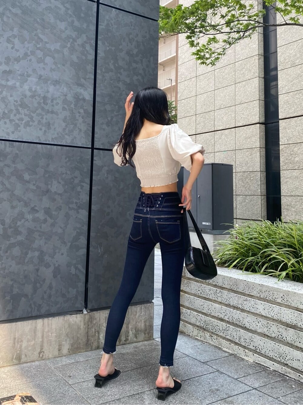 ブルー系のデニムパンツ、ホワイト系のTシャツ/カットソー、ブラック系のサンダルを着用したレディースの夏コーディネートの3枚目の写真