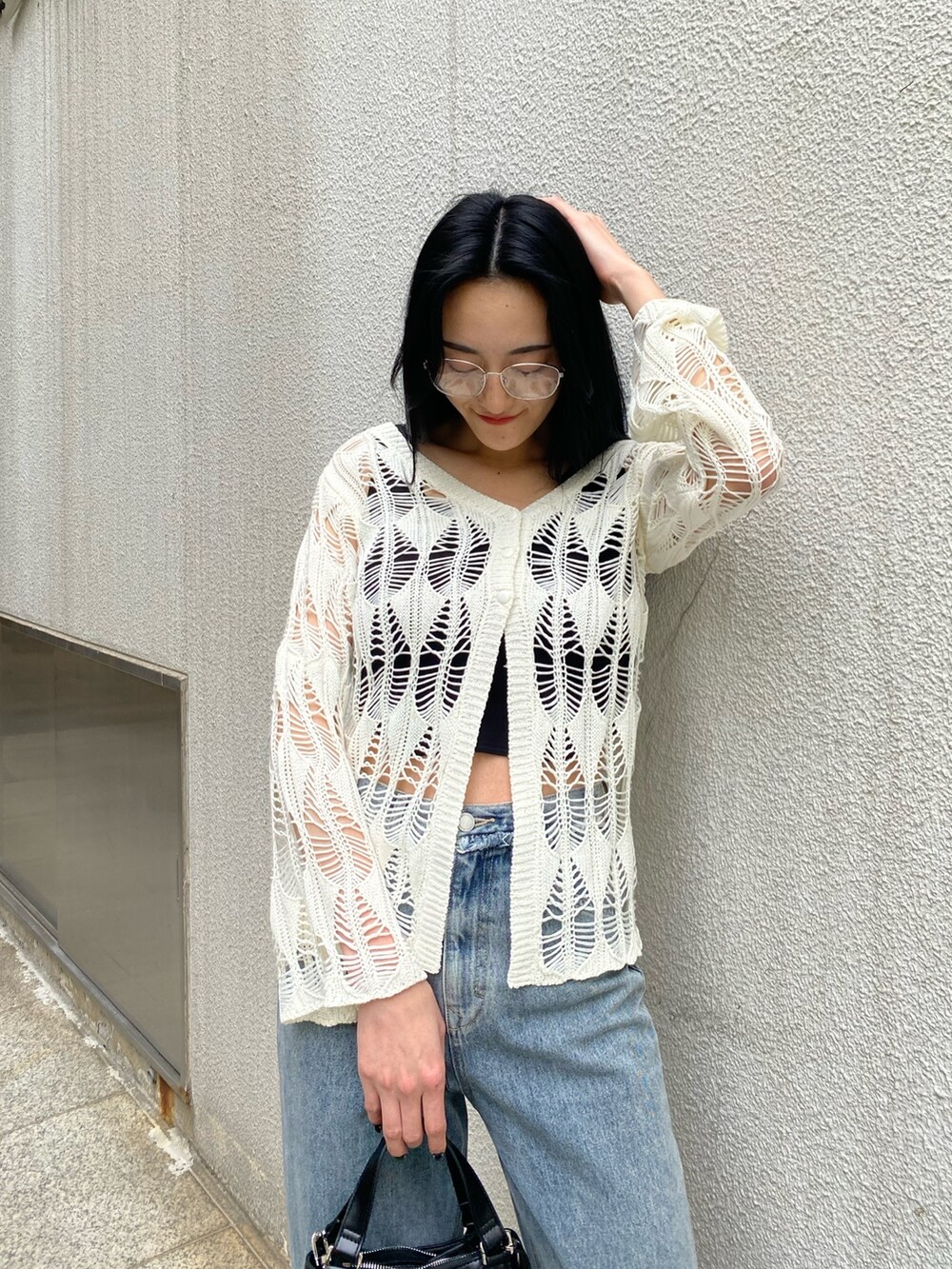 ブラック系のハンドバッグ、ブラック系のサンダル、ブルー系のデニムパンツを着用したレディースの春コーディネートの6枚目の写真