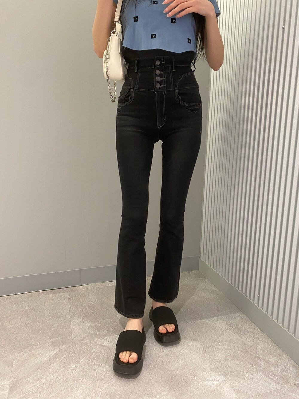 ブラック系のデニムパンツ、ブルー系のTシャツ/カットソー、ホワイト系のショルダーバッグを着用したレディースの春コーディネートの7枚目の写真