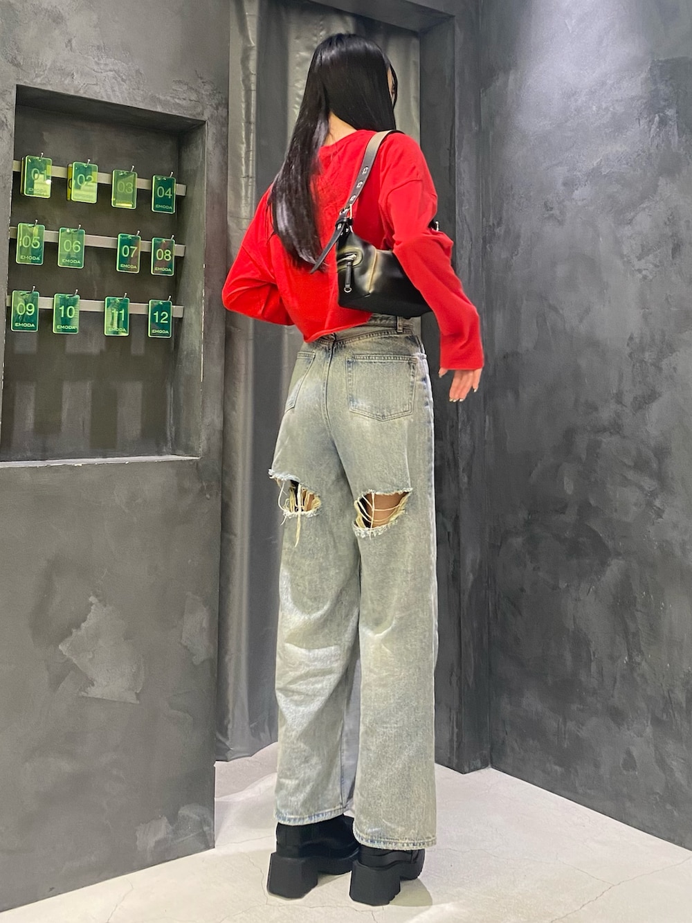 ブルー系のデニムパンツ、ブラック系のハンドバッグ、レッド系のTシャツ/カットソーを着用したレディースの秋コーディネートの4枚目の写真