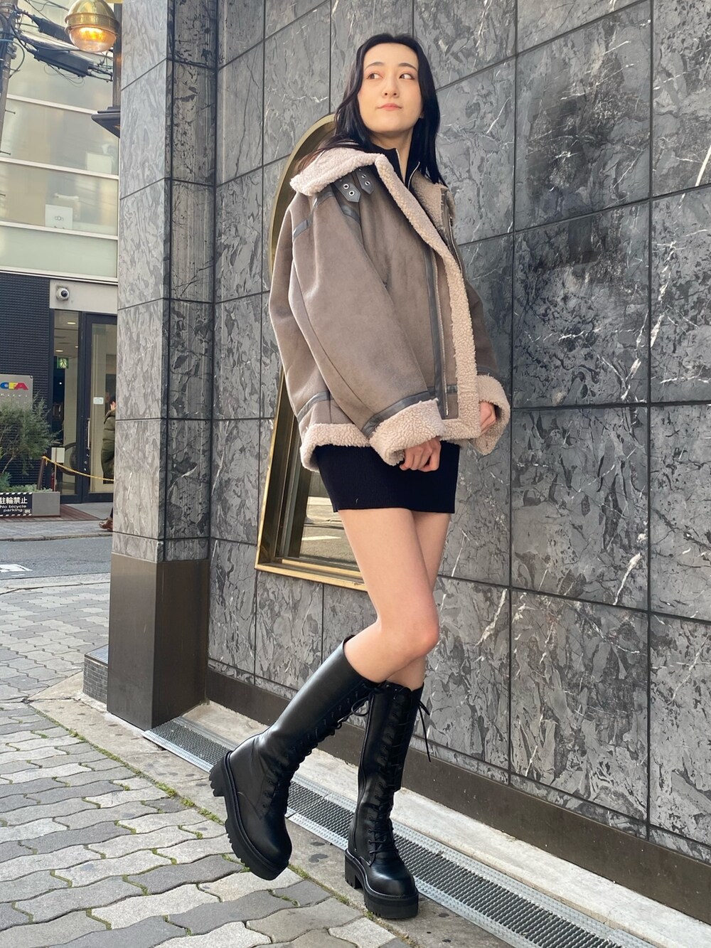 グレー系のブルゾン、ブラック系のワンピース、ブラック系のブーツを着用したレディースの冬コーディネートの3枚目の写真