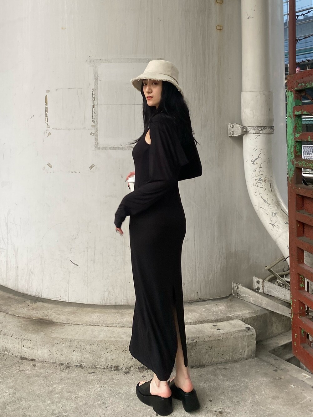 ブラック系のワンピース、ブラック系のサンダル、ホワイト系のハットを着用したレディースの春コーディネートの2枚目の写真