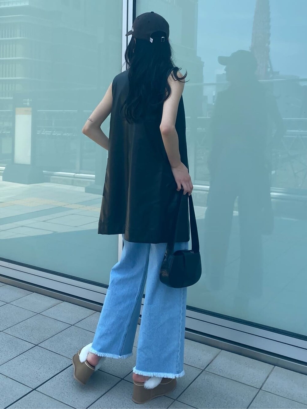 ブルー系のデニムパンツ、ブラック系のワンピース、ベージュ系のスリッポンを着用したレディースの夏コーディネートの4枚目の写真