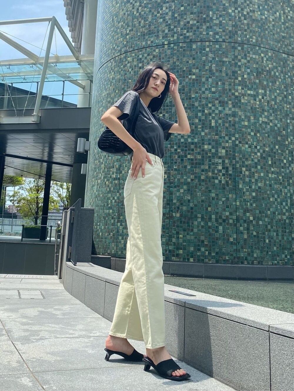 ホワイト系のデニムパンツ、ブラック系のサンダル、ブラック系のハンドバッグを着用したレディースの夏コーディネートの2枚目の写真