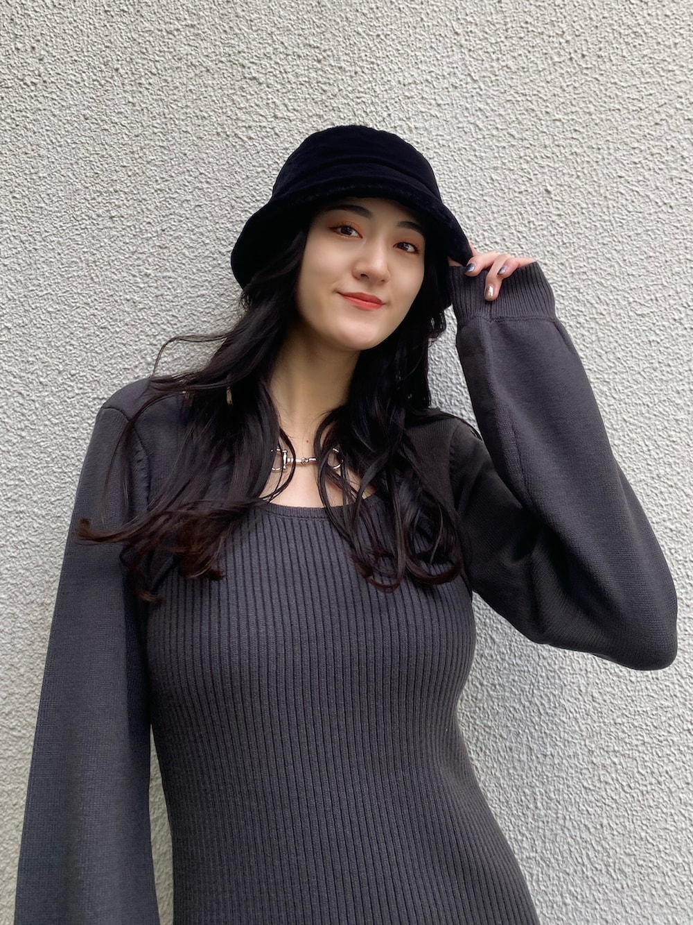 グレー系のワンピース、ブラック系のブーツ、ブラック系のハットを着用したレディースの冬コーディネートの4枚目の写真