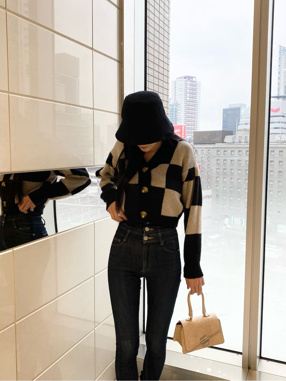 ブルー系のデニムパンツ、ブラック系のカーディガン/ボレロ、ベージュ系のハンドバッグを着用したレディースの冬コーディネートの3枚目の写真