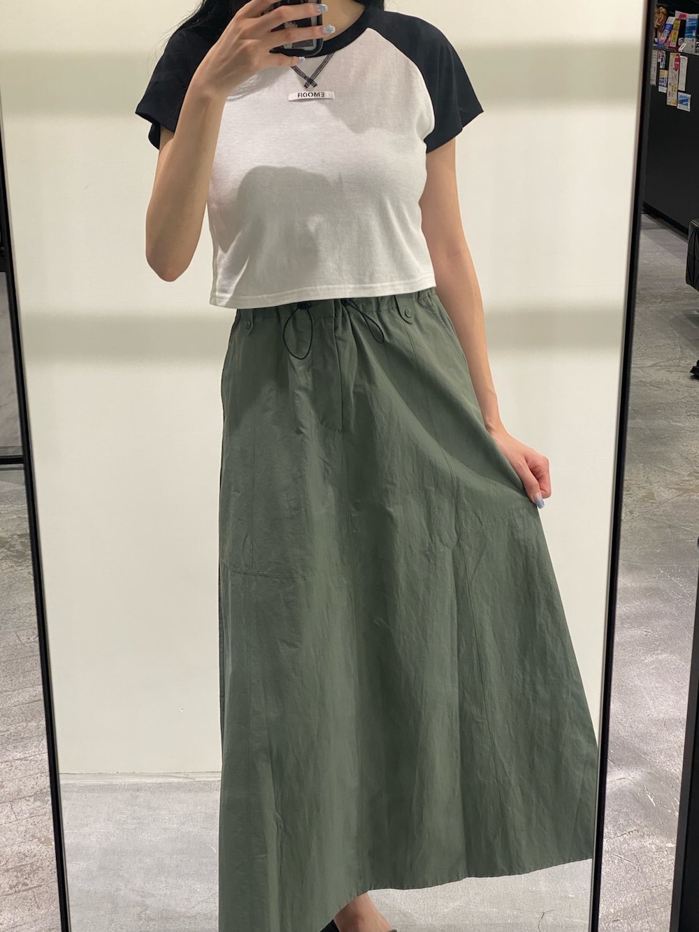 グリーン系のスカート、ブラック系のTシャツ/カットソー、ブラック系のサンダルを着用したレディースの夏コーディネートの2枚目の写真