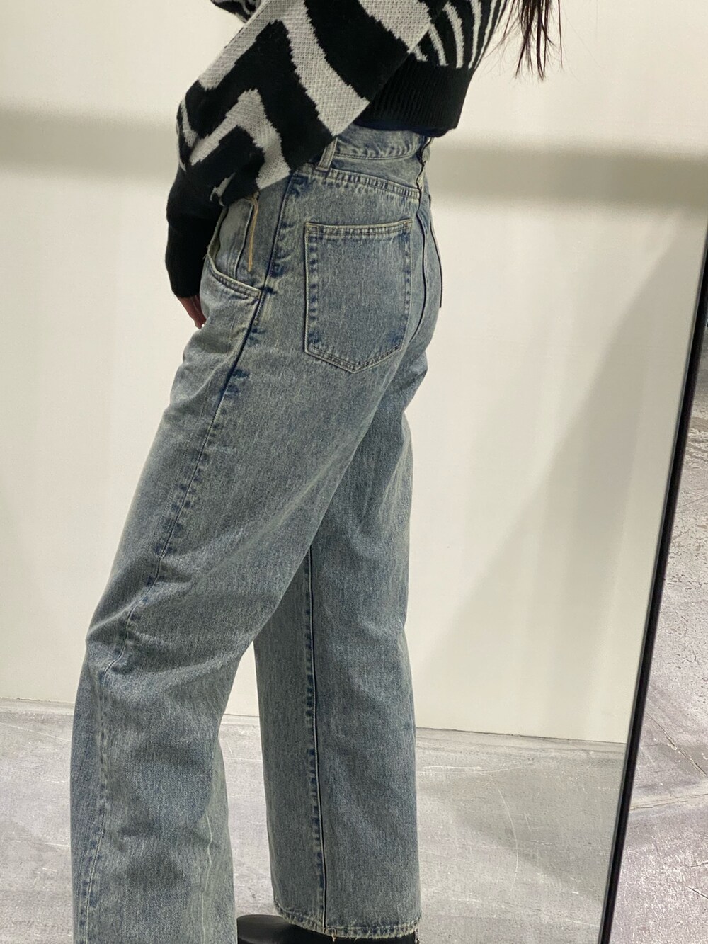 ブルー系のデニムパンツ、ブラック系のニット/セーター、ブラック系のブーツを着用したレディースの冬コーディネートの9枚目の写真