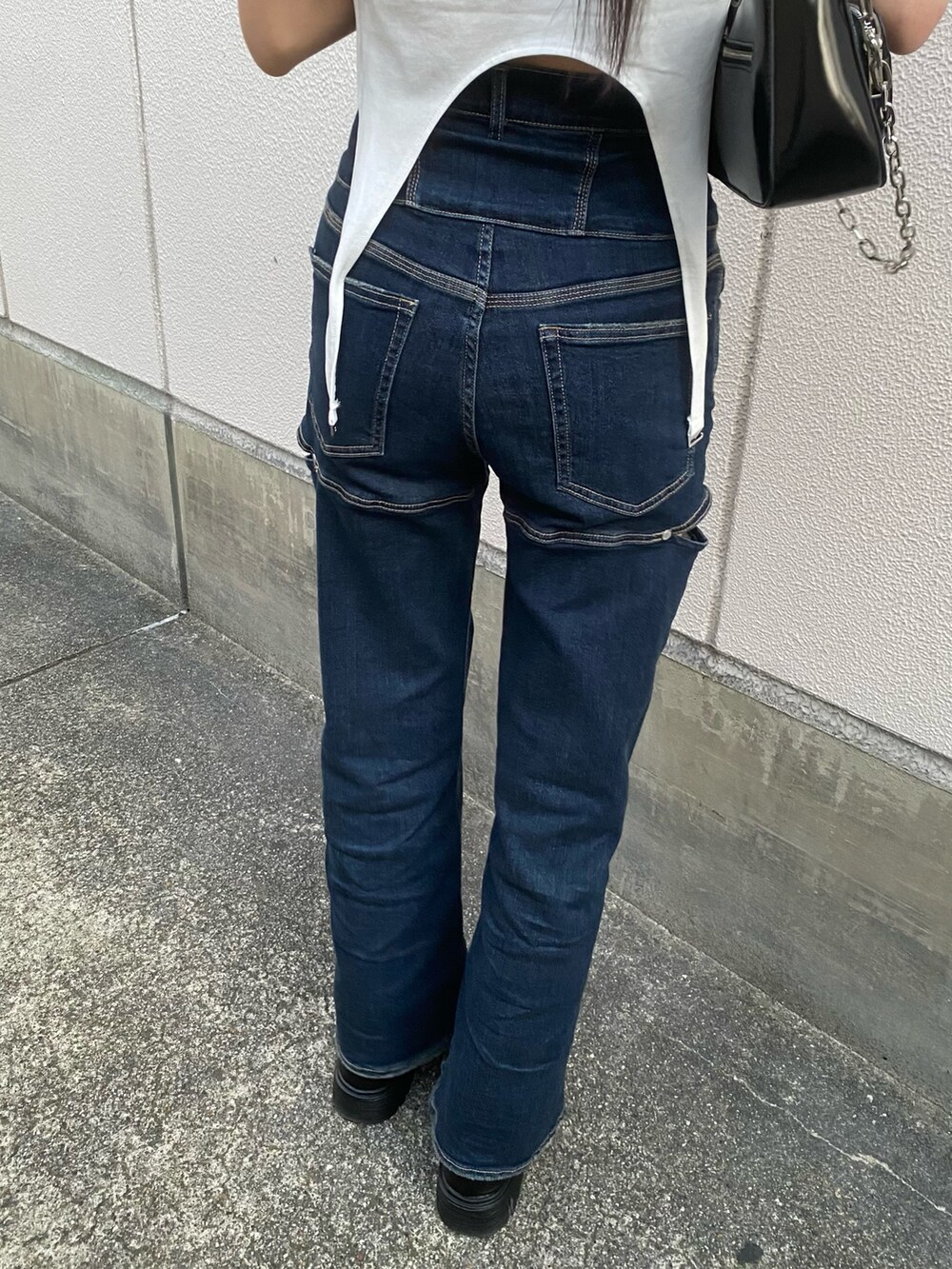 ブルー系のデニムパンツ、ブラック系のショルダーバッグ、ホワイト系のTシャツ/カットソーを着用したレディースの春コーディネートの8枚目の写真