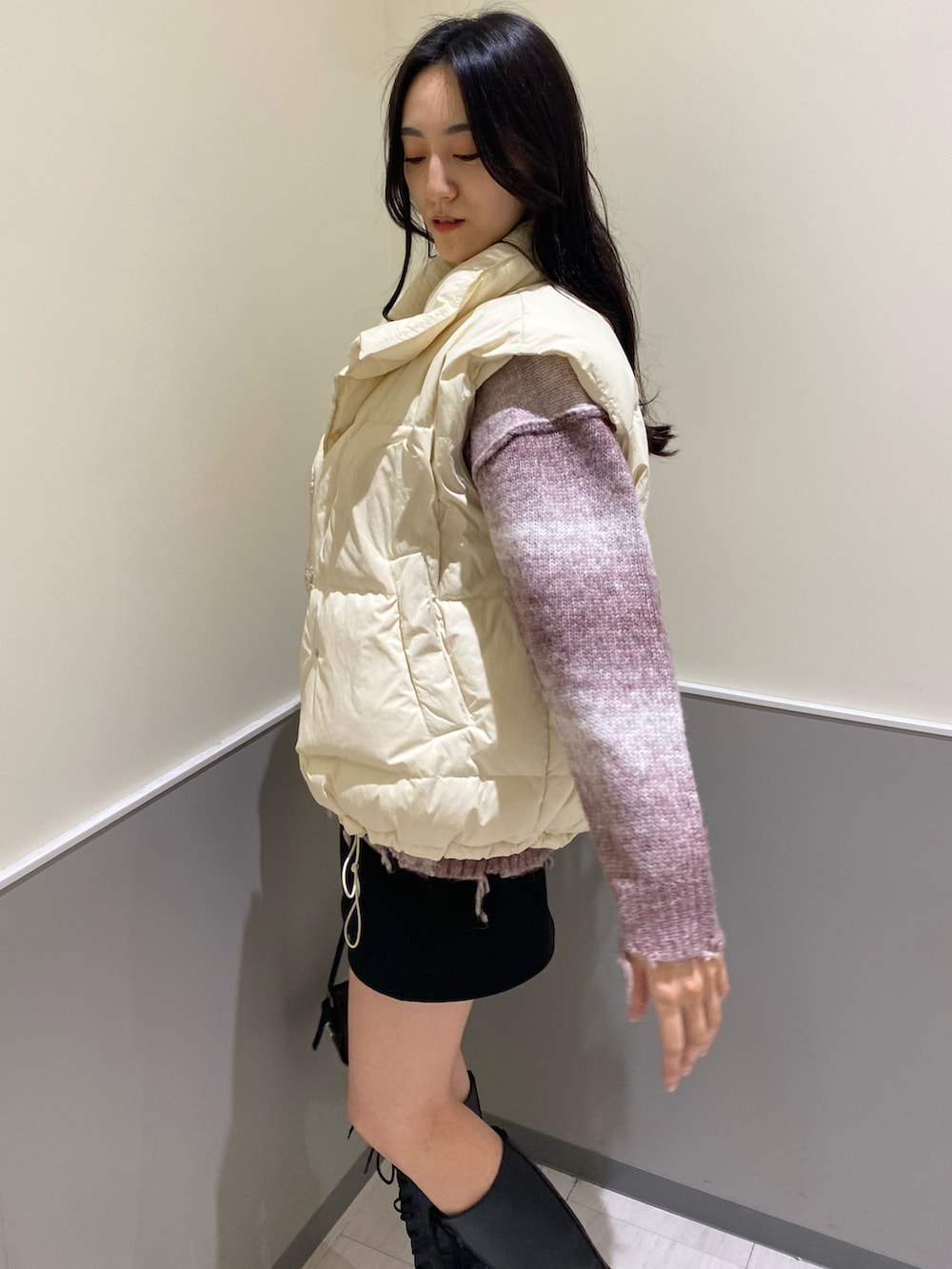 ブラック系のスカート、ピンク系のニット/セーター、ホワイト系のダウンベストを着用したレディースの秋コーディネートの4枚目の写真