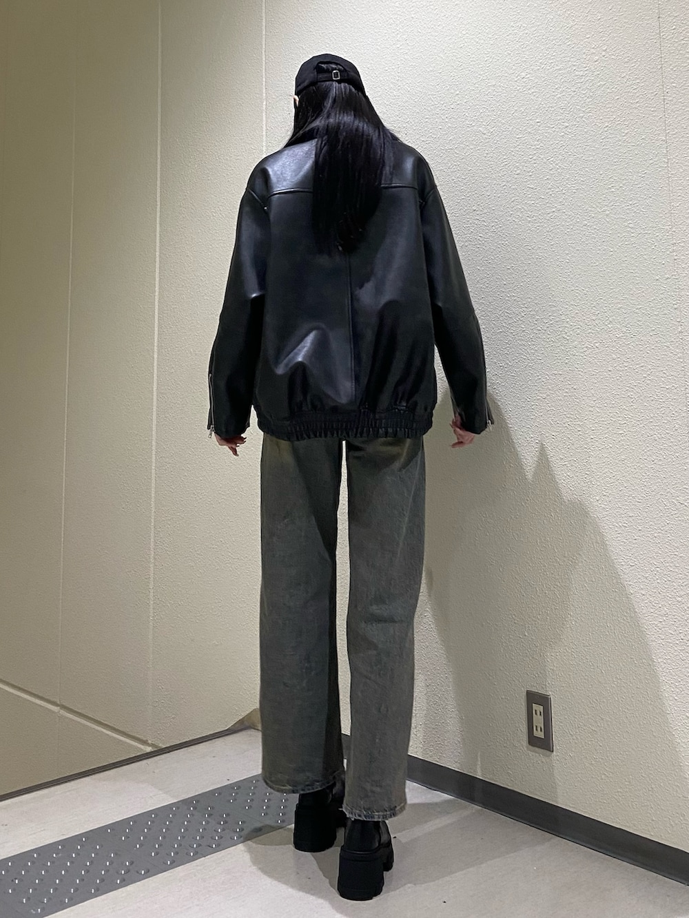 ブルー系のデニムパンツ、ブラック系のブルゾン、ブラック系のニット/セーターを着用したレディースの冬コーディネートの4枚目の写真