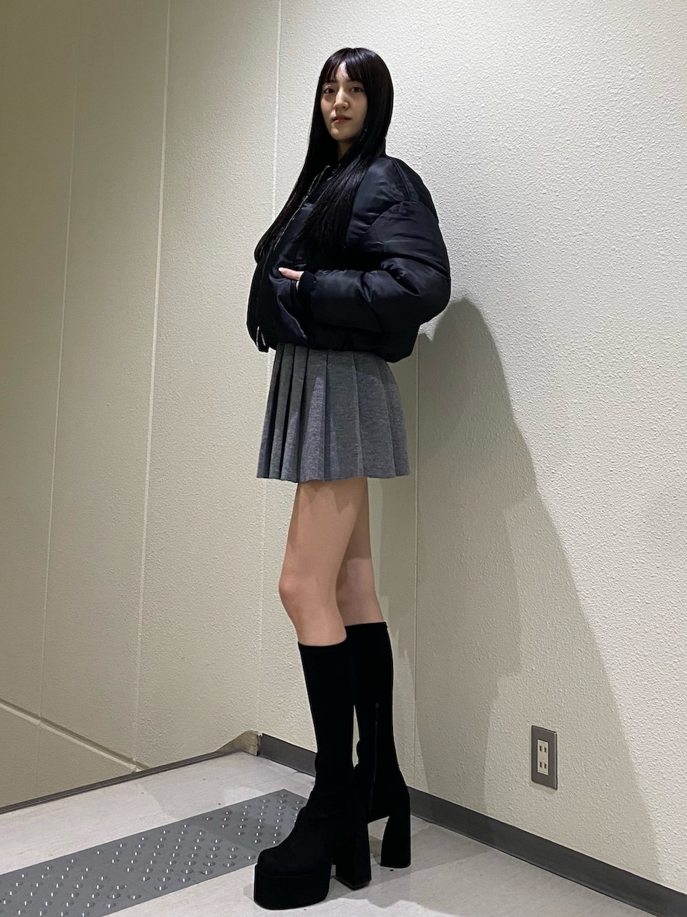 グレー系のスカート、ブラック系のブルゾン、その他のブーツを着用したレディースの秋コーディネートの2枚目の写真