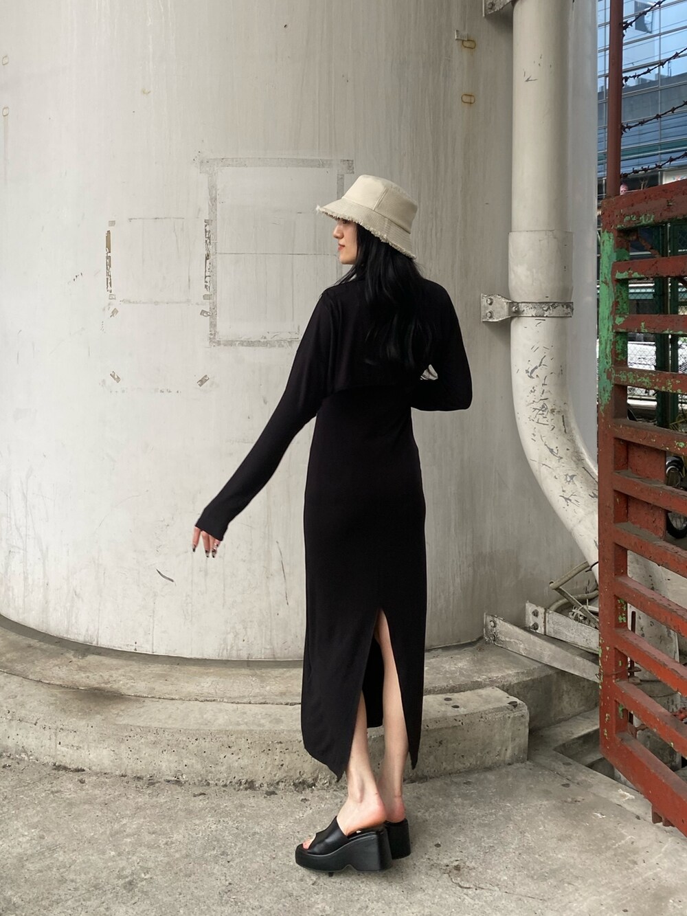 ブラック系のワンピース、ブラック系のサンダル、ホワイト系のハットを着用したレディースの春コーディネートの3枚目の写真
