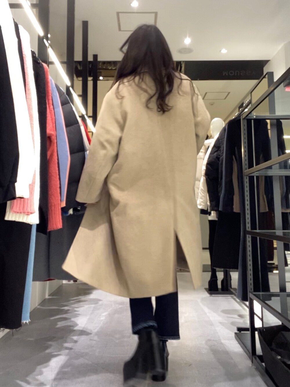 ベージュ系のチェスターコート、ブラック系のニット/セーター、ブルー系のデニムパンツを着用したレディースの冬コーディネートの2枚目の写真