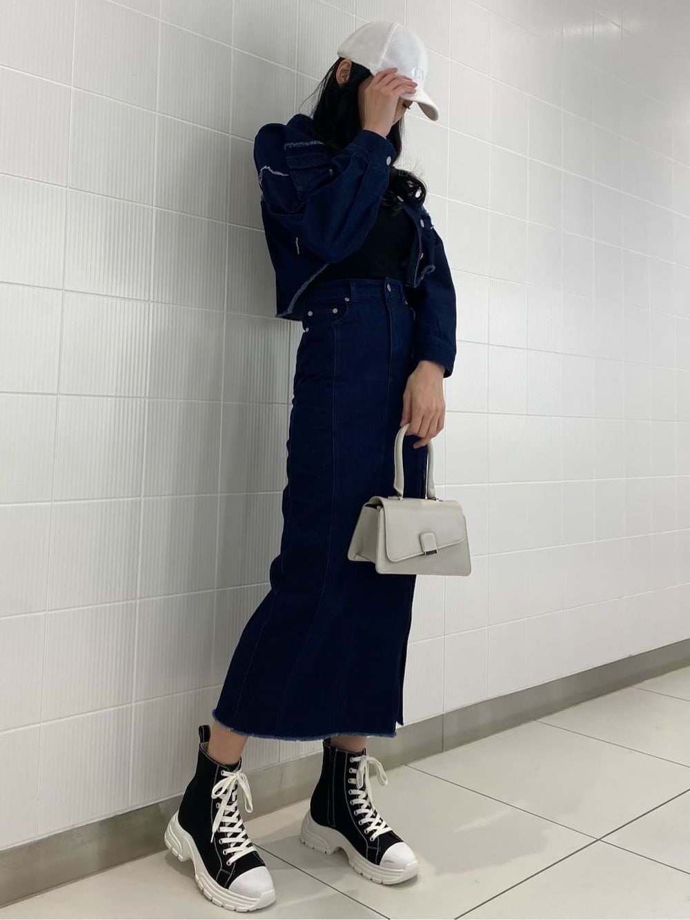 ブルー系のデニムジャケット、ブルー系のスカート、ホワイト系のハンドバッグを着用したレディースの夏コーディネートの3枚目の写真