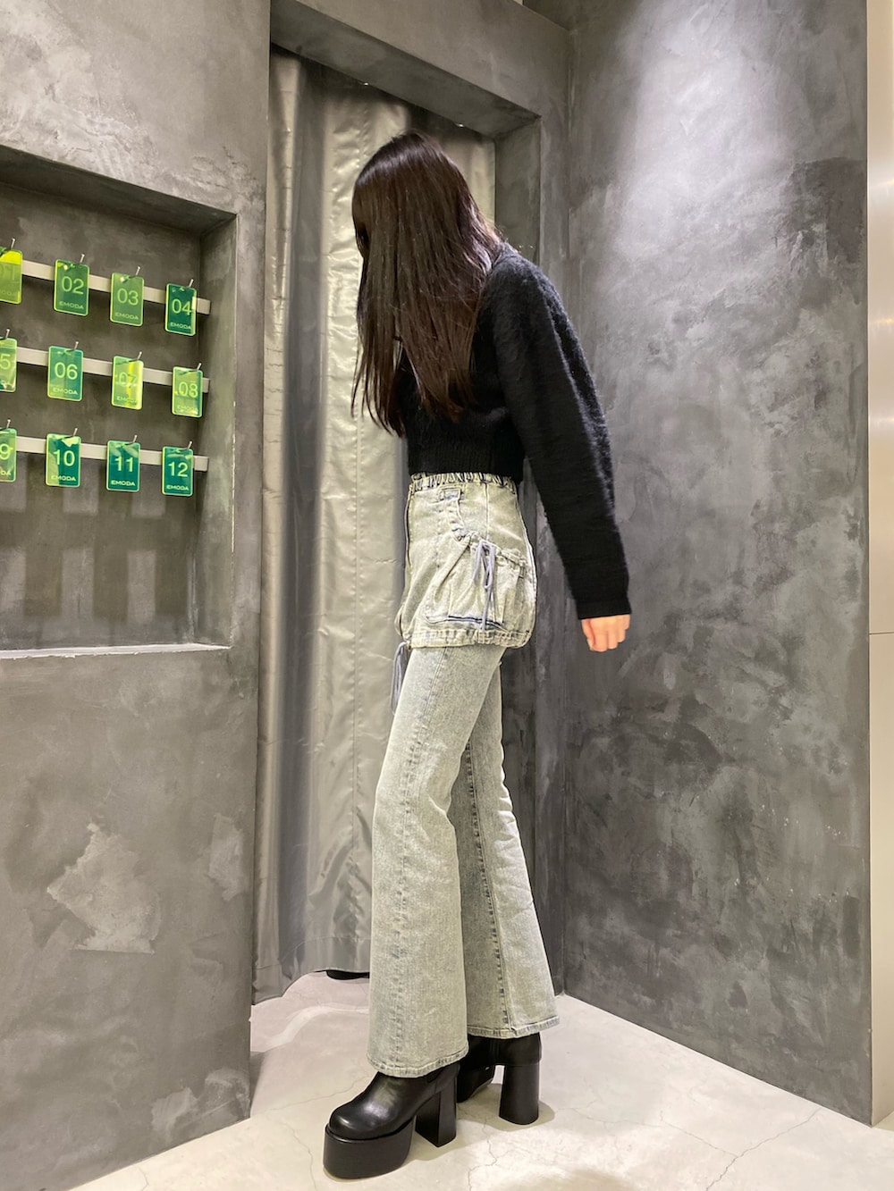 ブルー系のデニムパンツ、ブラック系のニット/セーター、ブラック系のブーツを着用したレディースの秋コーディネートの3枚目の写真