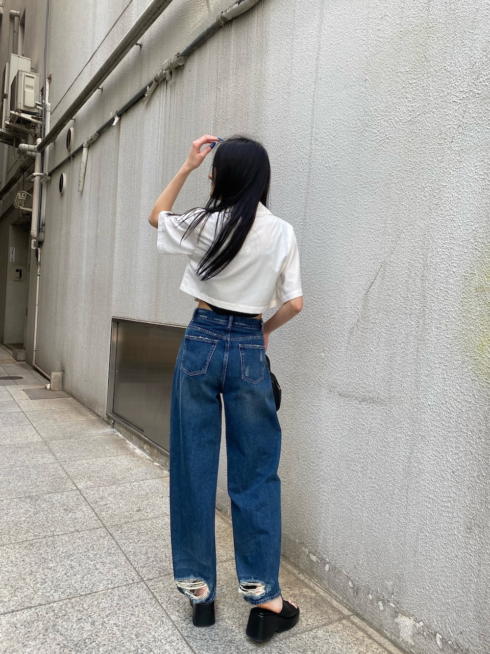 ブルー系のデニムパンツ、ブラック系のニット/セーター、ホワイト系のシャツ/ブラウスを着用したレディースの春コーディネートの4枚目の写真