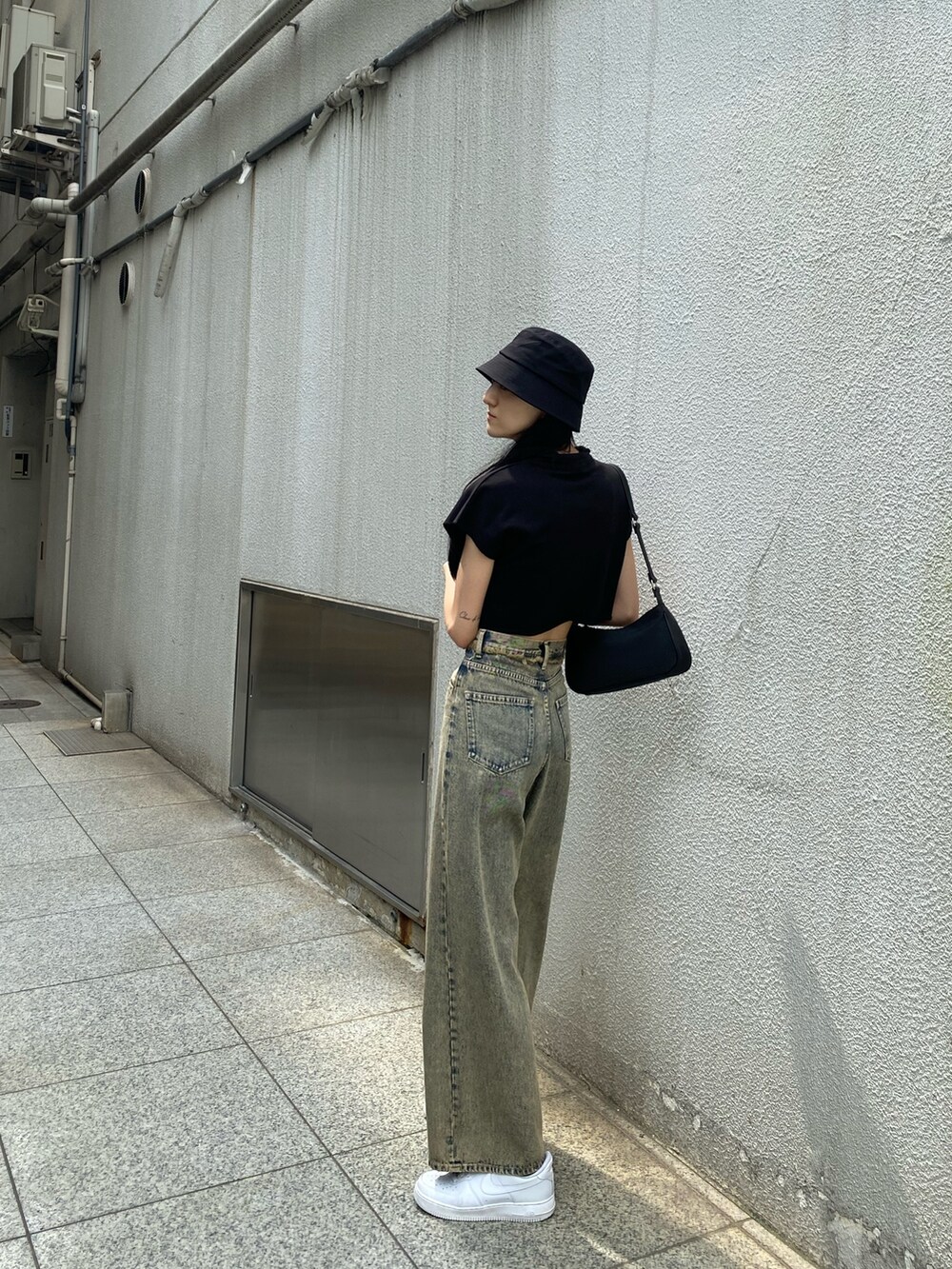 ブラック系のTシャツ/カットソー、ブラック系のハンドバッグ、ベージュ系のデニムパンツを着用したレディースの夏コーディネートの4枚目の写真