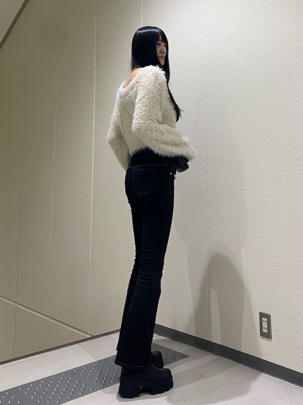 ホワイト系のニット/セーター、ブラック系のブーツ、ブラック系のデニムパンツを着用したレディースの冬コーディネートの5枚目の写真