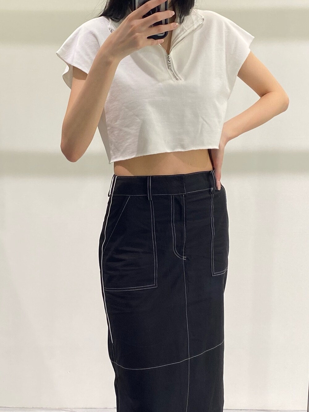 ブラック系のスカート、ホワイト系のTシャツ/カットソー、ブラック系のサンダルを着用したレディースの夏コーディネートの3枚目の写真