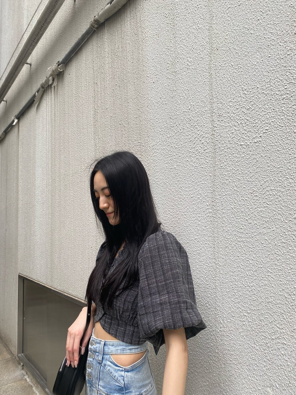 ブラック系のショルダーバッグ、ブラック系のTシャツ/カットソー、ブルー系のデニムパンツを着用したレディースの夏コーディネートの7枚目の写真