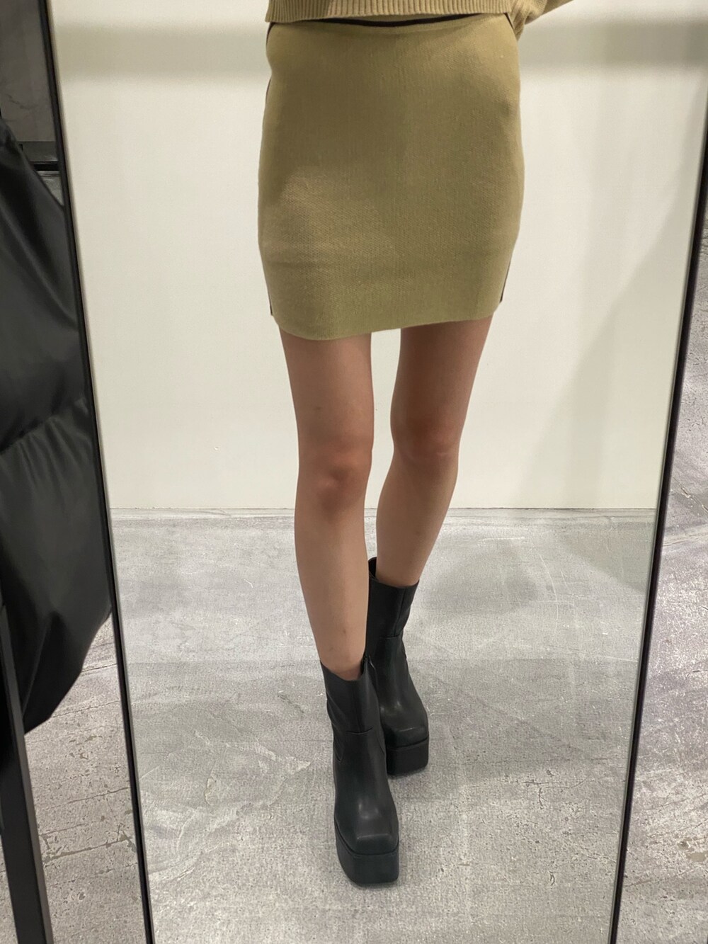 ベージュ系のニット/セーター、ベージュ系のスカート、ブラック系のブーツを着用したレディースの秋コーディネートの8枚目の写真