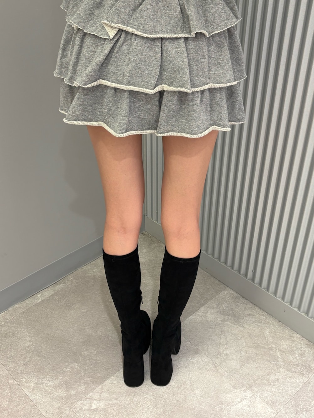 グレー系のスカート、ブラック系のニット/セーター、ブラック系のブーツを着用したレディースの秋コーディネートの9枚目の写真