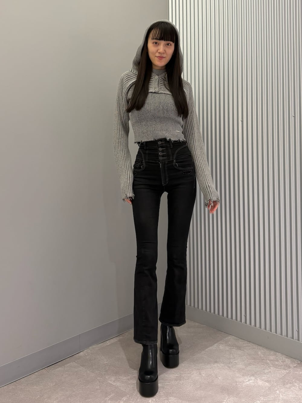 ブラック系のデニムパンツ、ブラック系のブーツ、グレー系のニット/セーターを着用したレディースの秋コーディネートの5枚目の写真