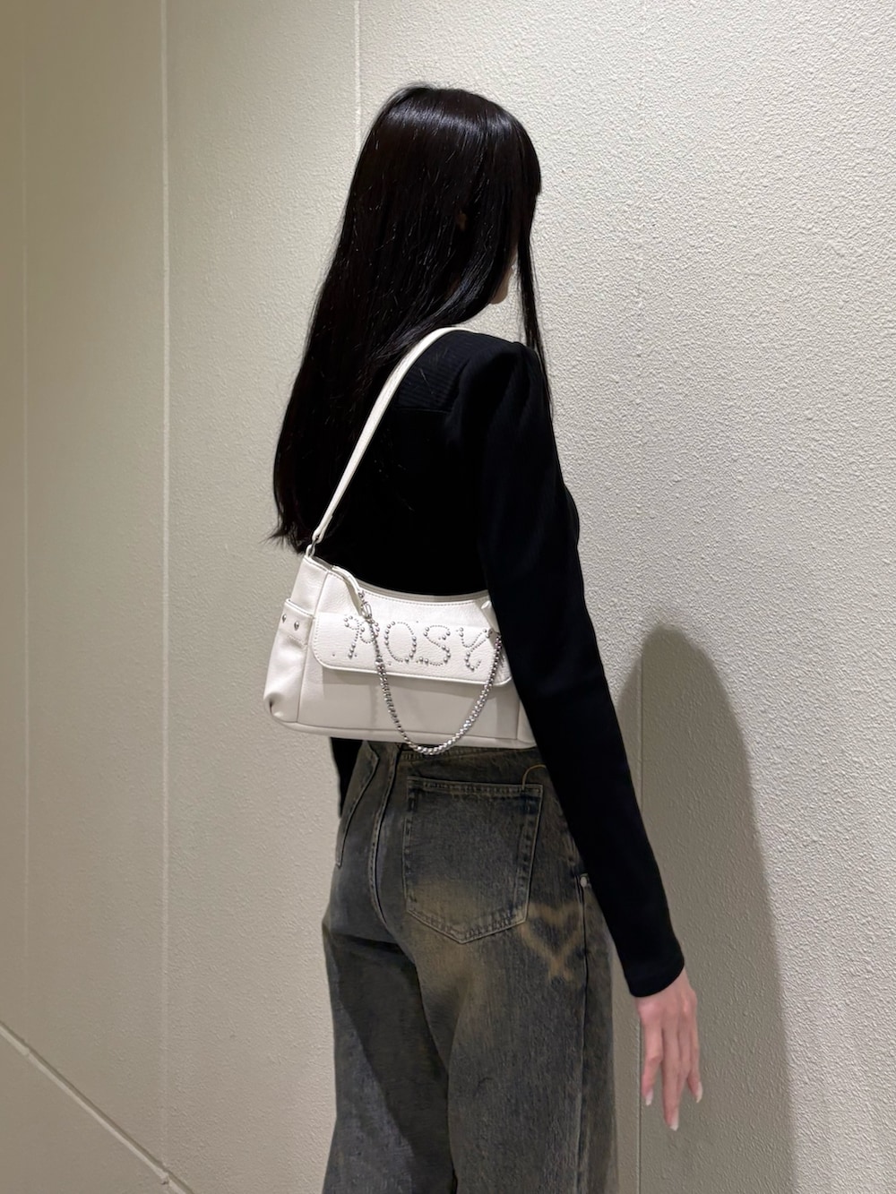 ブラック系のブーツ、ブルー系のデニムパンツ、ホワイト系のハンドバッグを着用したレディースの春コーディネートの9枚目の写真