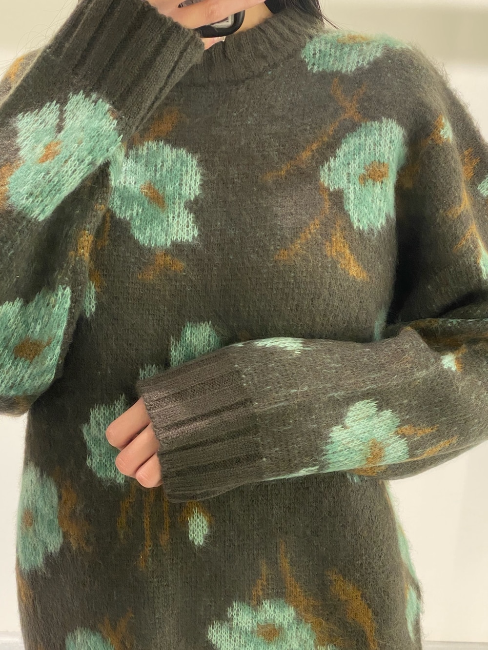 グリーン系のニット/セーター、ブラック系のスカート、ブラック系のブーツを着用したレディースの秋コーディネートの7枚目の写真