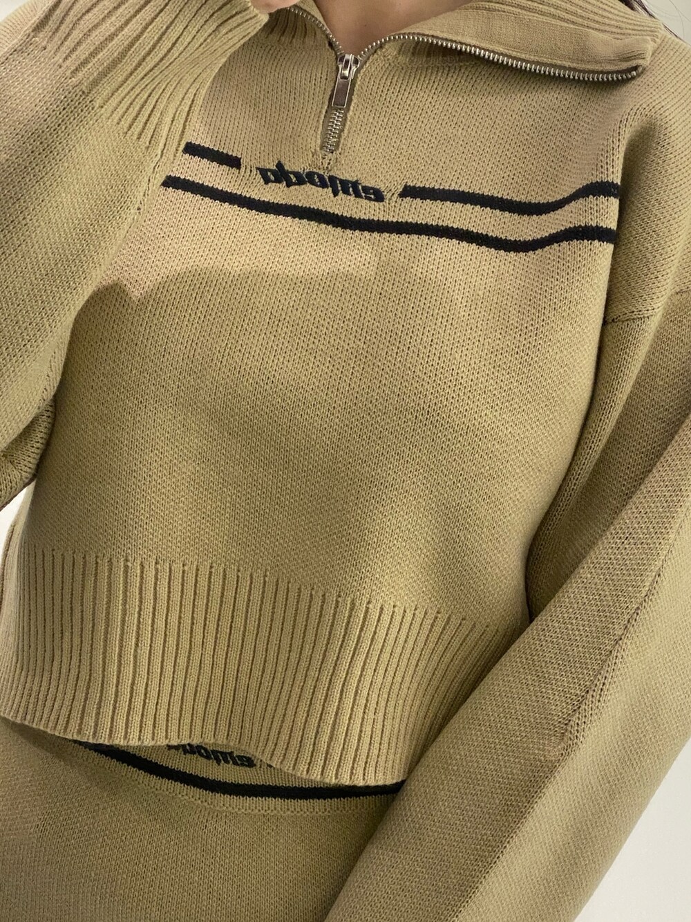 ベージュ系のニット/セーター、ベージュ系のスカート、ブラック系のブーツを着用したレディースの秋コーディネートの10枚目の写真