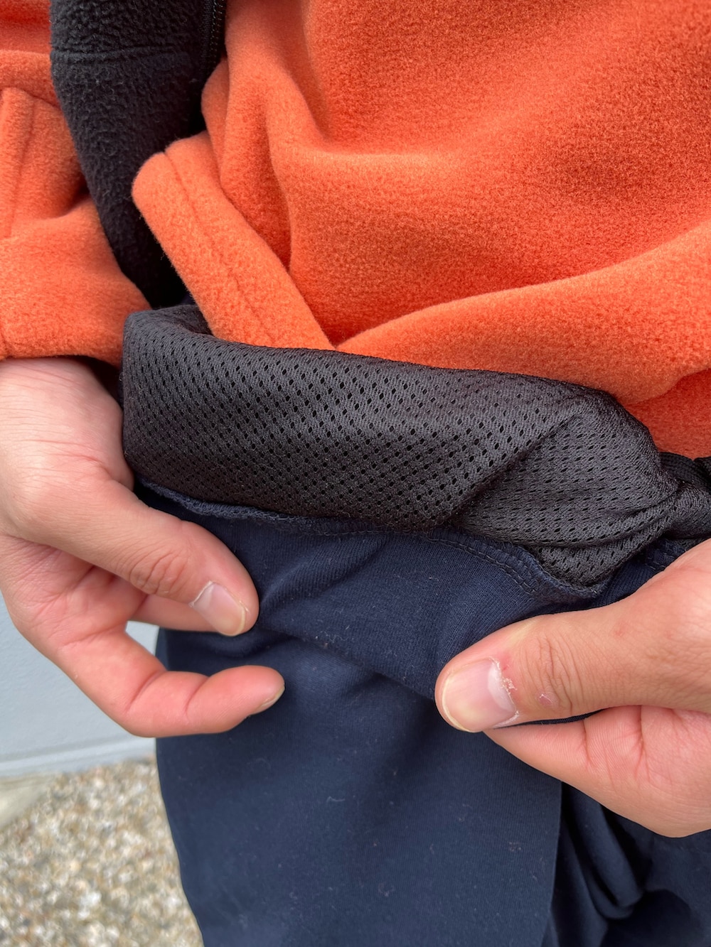 ブラック系のベスト、オレンジ系のスウェット、ブルー系のスウェットパンツを着用したメンズの冬コーディネートの2枚目の写真