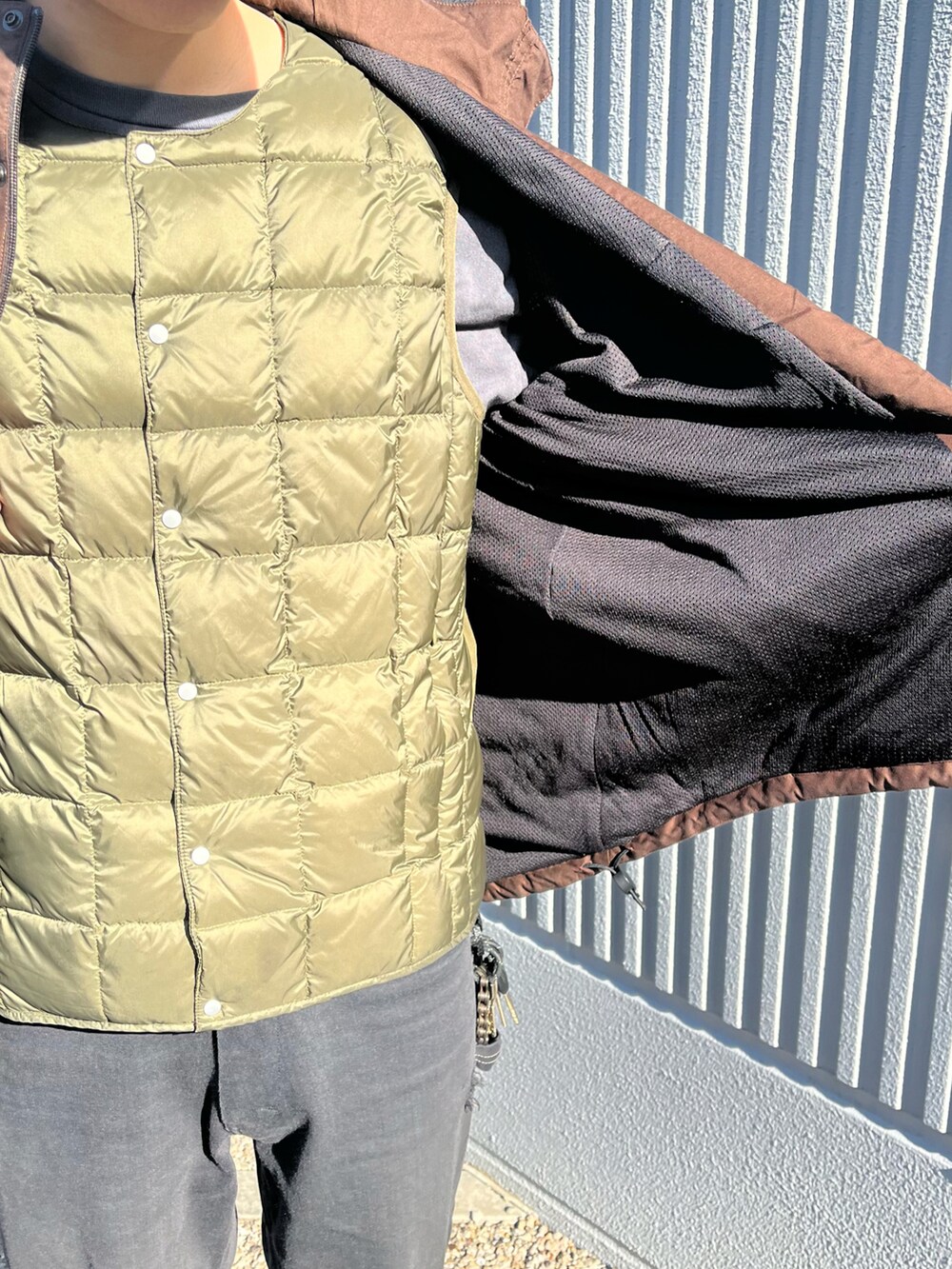 ベージュ系のスニーカー、ブラウン系のブルゾン、グリーン系のダウンベストを着用したメンズの冬コーディネートの2枚目の写真