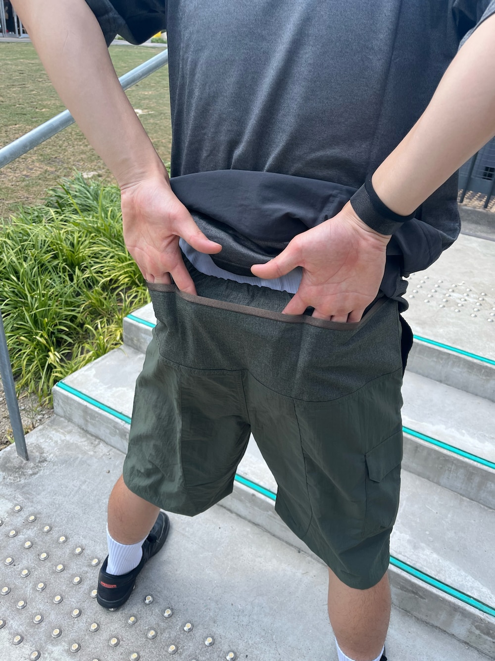 ブラック系のTシャツ/カットソー、グリーン系のカーゴパンツ、ブラック系のキャップを着用したメンズの夏コーディネートの3枚目の写真