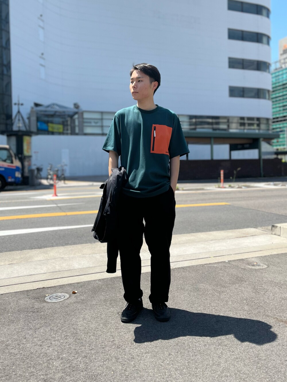 グリーン系のTシャツ/カットソー、ブラック系のナイロンジャケットを着用したメンズの春コーディネートの2枚目の写真