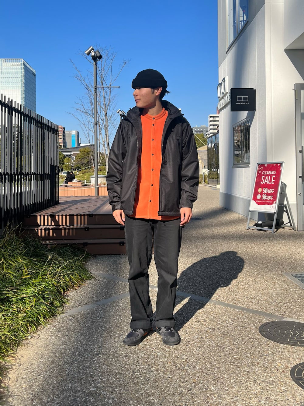ブラック系のマウンテンパーカー、オレンジ系のシャツ/ブラウス、ブラック系のスニーカーを着用したメンズの冬コーディネートの4枚目の写真