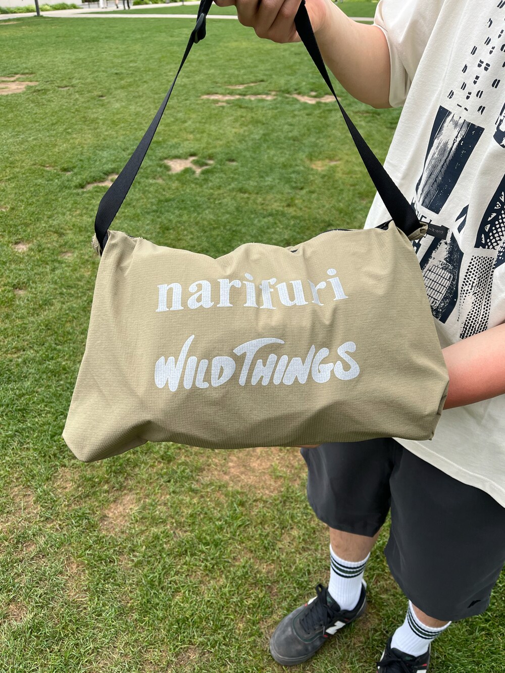 ブラック系のカーゴパンツ、ベージュ系のマウンテンパーカー、ホワイト系のTシャツ/カットソーを着用したメンズの春コーディネートの2枚目の写真