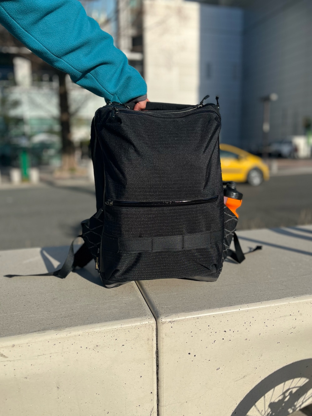 グレー系のパーカー、ブルー系のブルゾン、ブラック系のバックパック/リュックを着用したメンズの春コーディネートの3枚目の写真