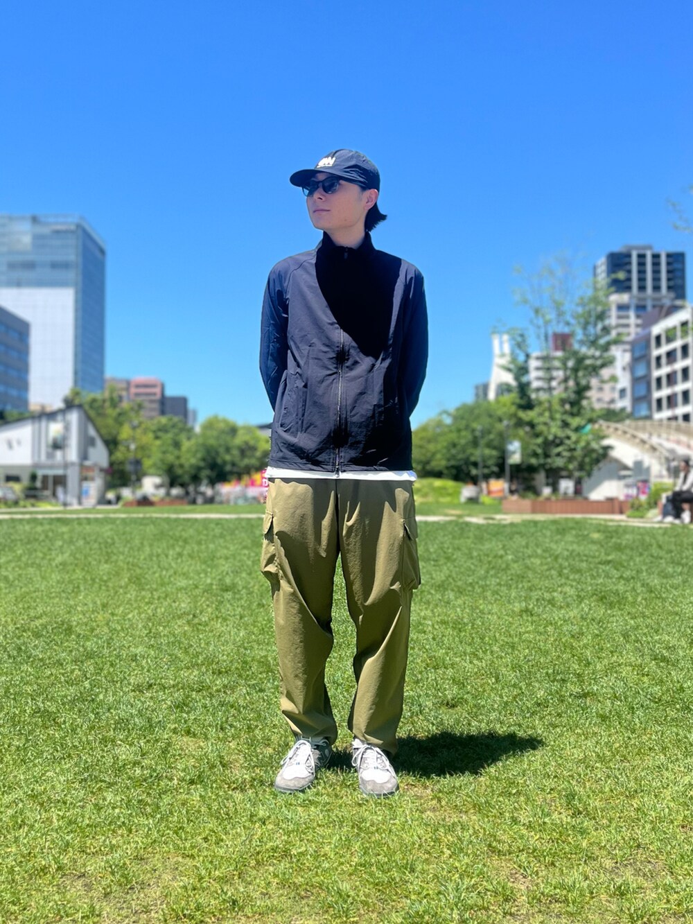 グリーン系のカーゴパンツ、ブラック系のブルゾン、ホワイト系のTシャツ/カットソーを着用したメンズの夏コーディネートの2枚目の写真