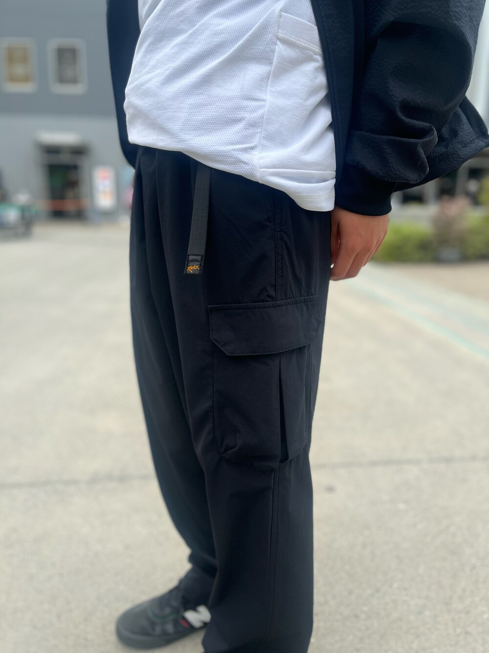 ブラック系のカーゴパンツ、ホワイト系のTシャツ/カットソー、ブラック系のブルゾンを着用したメンズの春コーディネートの2枚目の写真