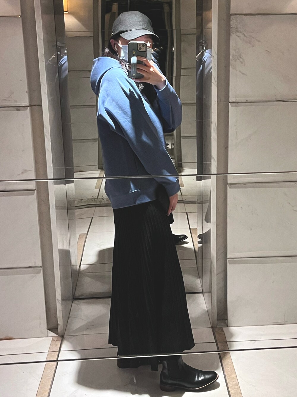 ブルー系のパーカー、ブラック系のスカート、ブラック系のキャップを着用したレディースの秋コーディネートの2枚目の写真