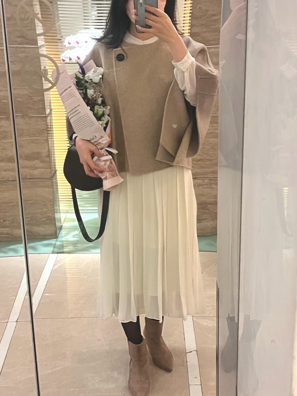 ホワイト系のシャツワンピース、ベージュ系のブーツ、ベージュ系のポンチョを着用したレディースの秋コーディネートの2枚目の写真