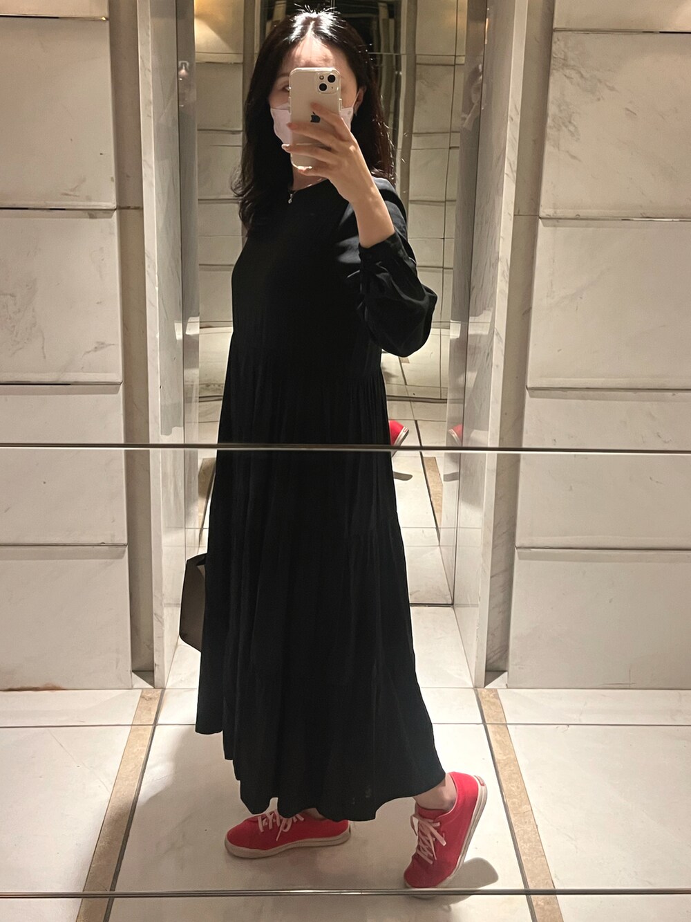 レッド系のスニーカー、グレー系のハンドバッグ、ブラック系のワンピースを着用したレディースの秋コーディネートの2枚目の写真
