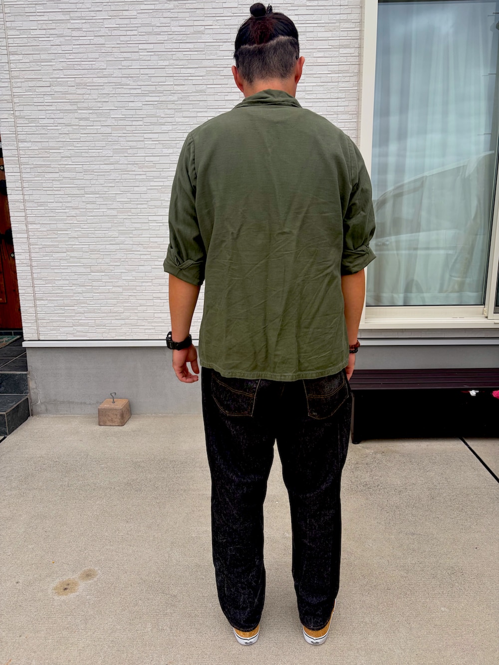 ブラック系のTシャツ/カットソー、グリーン系のミリタリージャケット、ブラック系のデニムパンツを着用したメンズの秋コーディネートの2枚目の写真